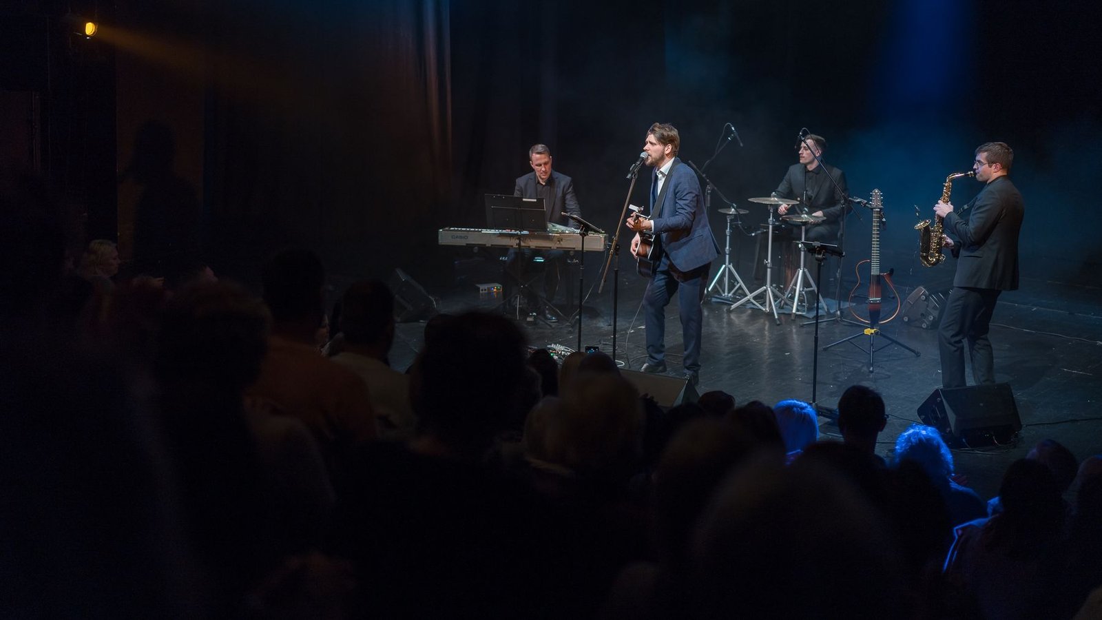 The band with saxophone and keyboards on a concert stage